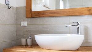 A bathroom with a wooden vanity, a white sink, and a mirror.