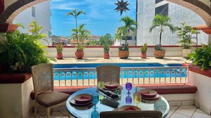 Ein Balkon mit Pool, Topfpflanzen und einem Essplatz.