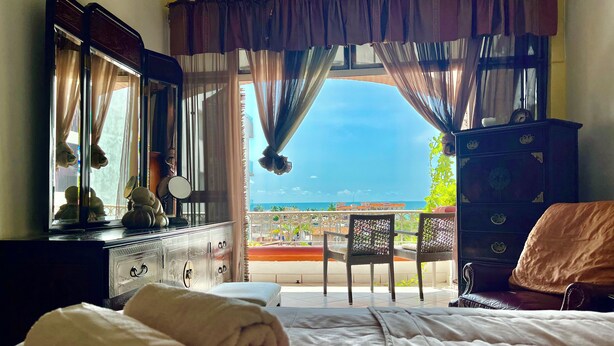 Ein Hotelzimmer mit Bett, Schminktisch, Spiegel und Meerblick.