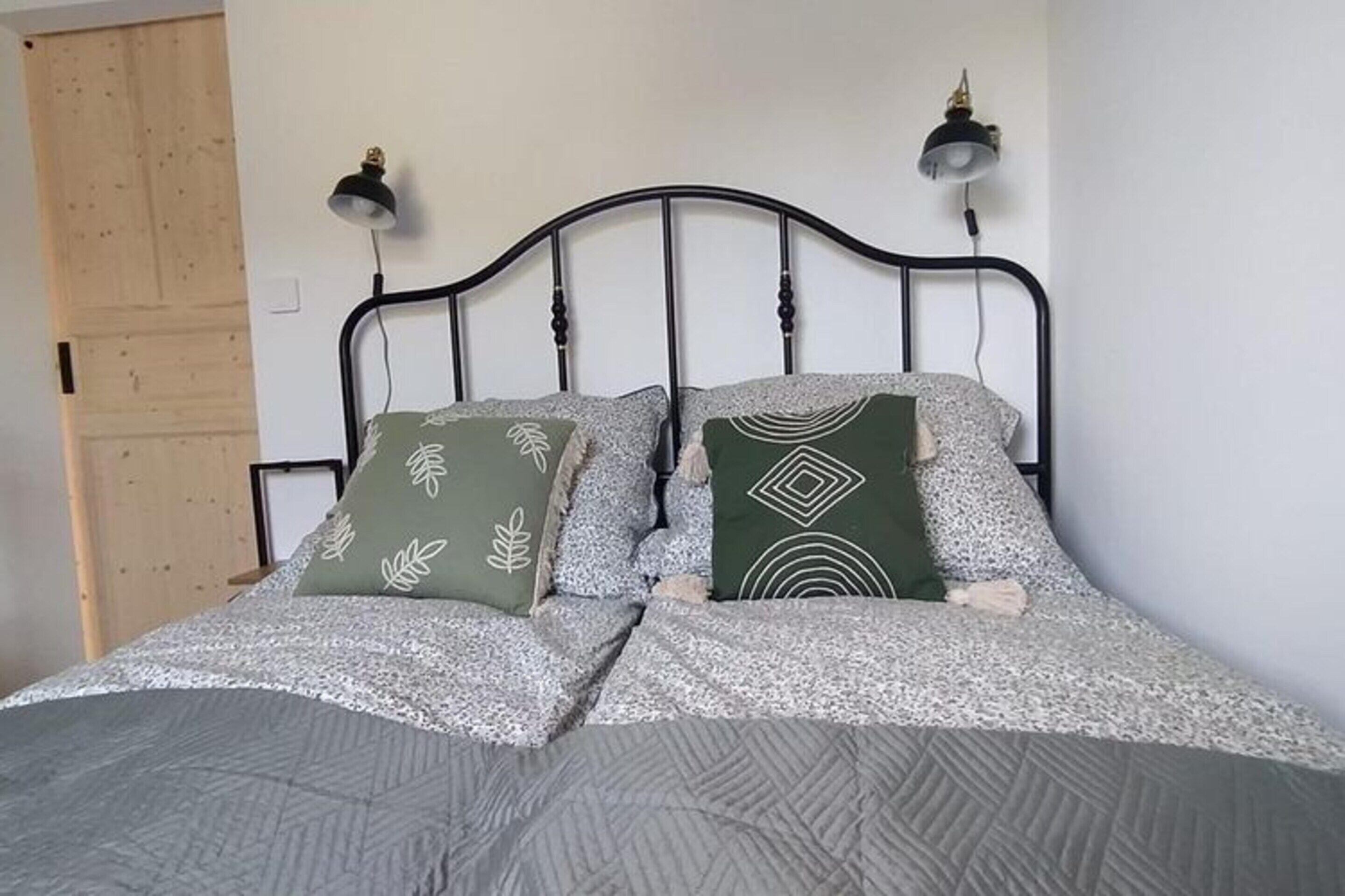 A bed with a metal frame, two bedside lamps, and patterned pillows.