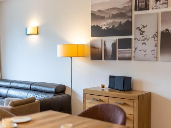 Ein modernes Hotelzimmer mit einer Ledersofa, einem Holznachttisch, einer Lampe und gerahmten Bildern an der Wand.