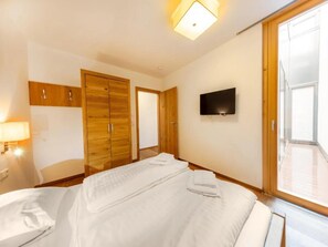 Une chambre d’hôtel avec un lit, un téléviseur fixé au mur et une fenêtre.