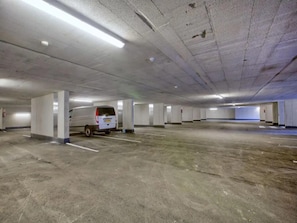 A multi-level parking garage with concrete floors and walls, and a white van parked in one of the spaces. - Modern Neukirchen Apartment for 8 (Neukirchen am Grossvenediger)