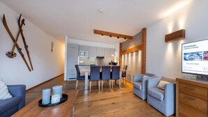 Un soggiorno moderno con un tavolo da pranzo in legno, un divano e una TV su un mobile in legno.