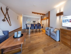 Ein modernes Wohnzimmer mit einem Holzesstisch, einer Couch und einem Fernseher auf einer Holzkommode.