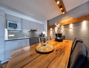 Una cocina moderna con gabinetes grises, un microondas integrado y una mesa de comedor de madera con un florero.