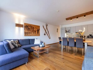 Una sala de estar moderna con un sofá azul, una mesa de centro de madera y un comedor con mesa y sillas de madera.