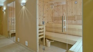 Una sauna con parete divisoria in vetro, panche di legno e una panca con un asciugamano.