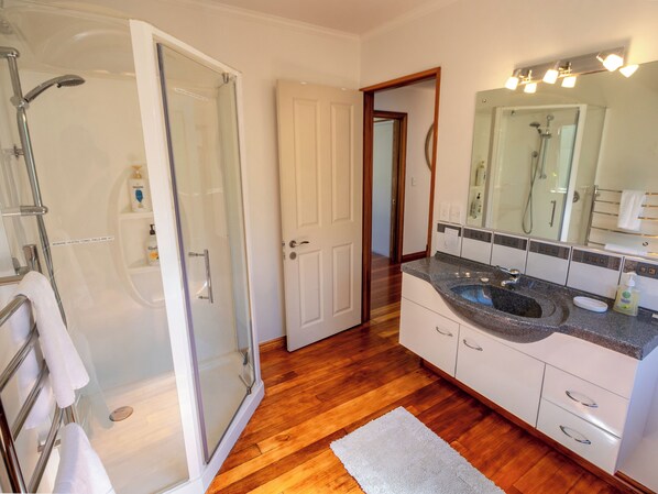 A modern bathroom with a glass shower enclosure, a vanity with a sink, and a large mirror.