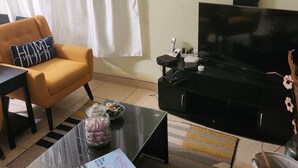 A living room with a sofa, a coffee table, a TV, and decorative wall art. - Matilda Ville – Long-Term 2BR Retreat, The Whim, St. Peter, Barbados. (The Whim)