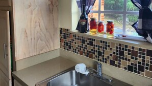 A kitchen with a marble countertop, a stainless steel sink, and a window with curtains. - Matilda Ville – Long-Term 2BR Retreat, The Whim, St. Peter, Barbados. (The Whim)