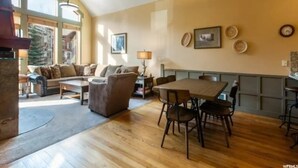 A spacious living area with a wooden floor, a dining table with chairs, a sofa, and a lamp. - 4 bdr Swiss chalet in Solitude, 5 min to lifts (Salt Lake City)