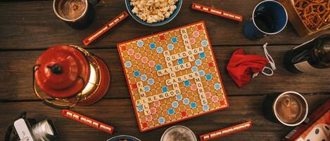 A board game, snacks, drinks, and a camera on a wooden table.