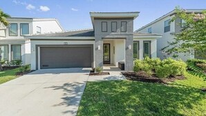 Ein modernes, zweistöckiges Haus mit Garage, überdachter Eingangspartei und gepflegtem Rasen.