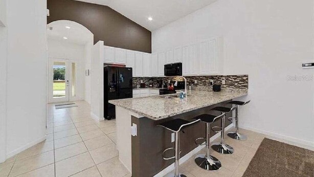 Eine moderne Küche mit einer zentralen Kochinsel, Barhocker und einer Mikrowelle.