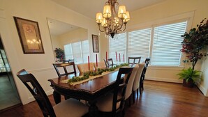 A dining room with a wooden table, six chairs, a chandelier, and a potted plant. - 13. King bed, sleeps 22, historic 5-bedroom house in  Albertville with WiFi, AC (Albertville)