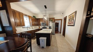 A modern kitchen with wooden cabinets, a central island, and a dining area with a table and chairs. - 13. King bed, sleeps 22, historic 5-bedroom house in  Albertville with WiFi, AC (Albertville)