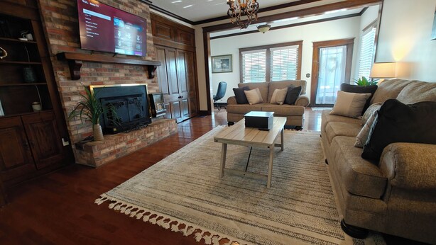 A living room with a fireplace, a television mounted on the wall, a sofa, and a coffee table. - 13. King bed, sleeps 22, historic 5-bedroom house in  Albertville with WiFi, AC (Albertville)