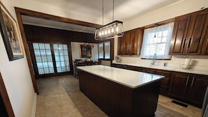 A spacious kitchen with a large island, wooden cabinets, and a modern chandelier. - 13. King bed, sleeps 22, historic 5-bedroom house in  Albertville with WiFi, AC (Albertville)