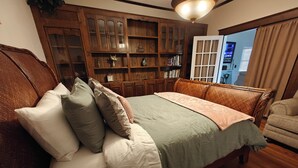 A bedroom with a wooden bed, a large wooden bookshelf, and a view of the outside through a door. - 13. King bed, sleeps 22, historic 5-bedroom house in  Albertville with WiFi, AC (Albertville)