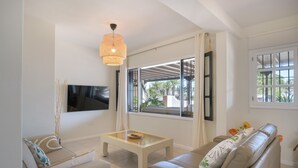 A modern living room with a sofa, a coffee table, and a TV mounted on the wall.