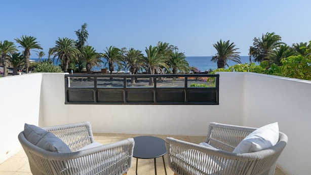 A terrace with wicker furniture and a view of the sea.