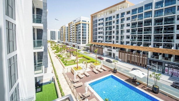 A modern hotel with a rooftop pool, multiple floors, and a landscaped garden area.