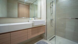 A modern bathroom with a glass shower enclosure, a wooden vanity, and a large mirror above the sink.