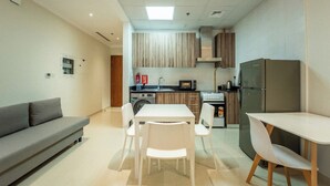 A compact living space with a kitchenette, a dining area with a table and chairs, and a sofa. - AWS Holiday Homes - In the Heart of Downtown (Dubai)