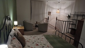 Ein Schlafzimmer mit Bett, Nachttisch, Lampe und Blick auf eine Treppe.