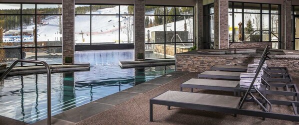 Une piscine intérieure offrant une vue dégagée sur une montagne enneigée et un télésiège.
