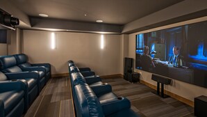 Ein Heimkino mit großem Flachbildfernseher, blauen Ledersessel mit Liegefunktion und Holzboden.