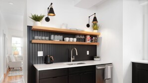 A modern kitchen with dark cabinetry, a white countertop, and black pendant lights. - Fox Point 3BR - Near Brown, RISD & Downtown (Providence)