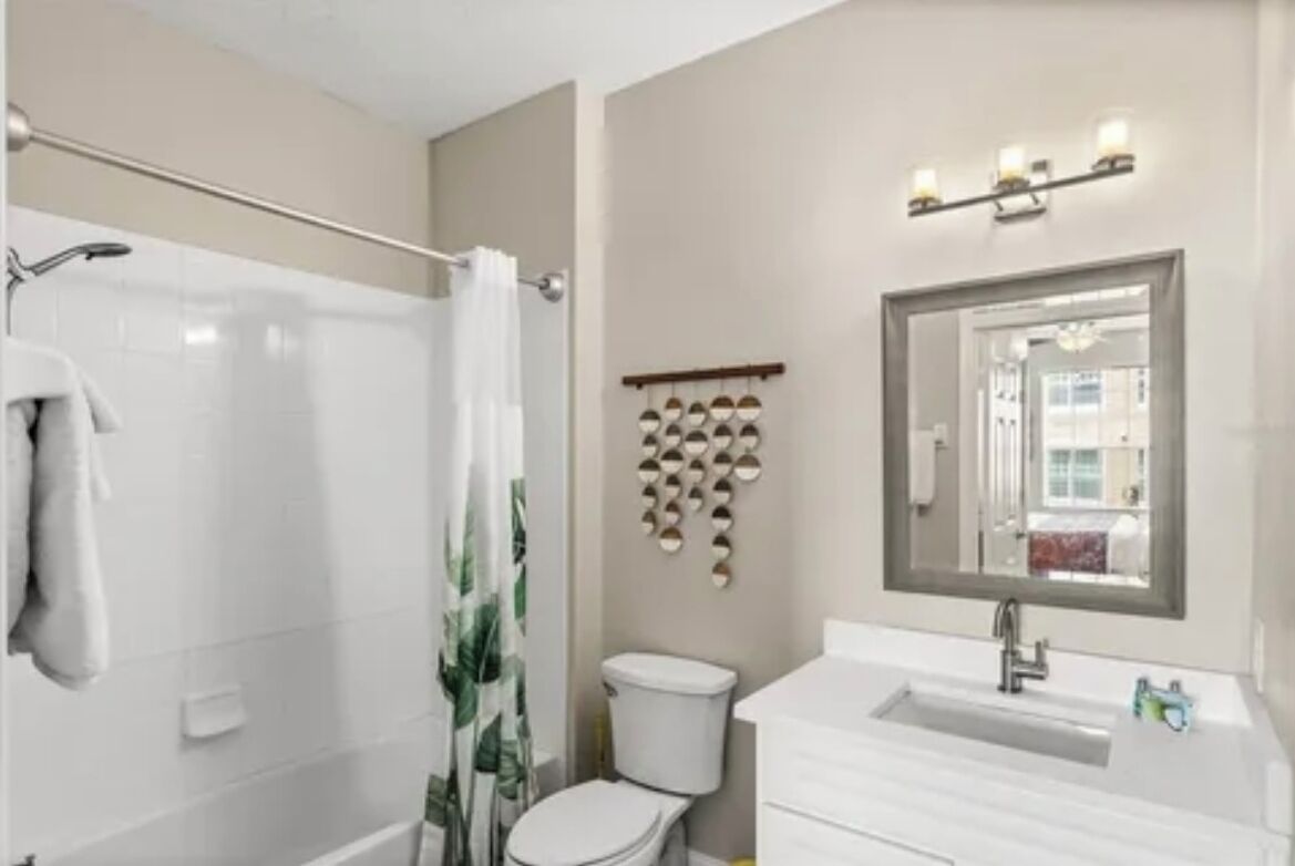 Een badkamer met douche, toilet, wastafel en spiegel.