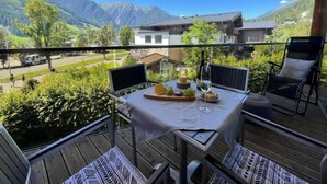 A balcony with a table set for two, overlooking a mountainous landscape. - Top-floor Mountain Penthouse for 8 (Neukirchen am Grossvenediger)