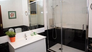 A modern bathroom with a glass-enclosed shower, a white sink with a potted plant, and a large mirror. - APARTMENT GRANVIA FIRA BCN🎅🏻 (Hospitalet de Llobregat)
