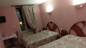 A bedroom with two single beds, a desk, and a window with curtains. - Hôtel de l'Europe (Corbigny)