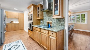 A kitchen with wooden cabinets, granite countertops, stainless steel appliances, and a large window.