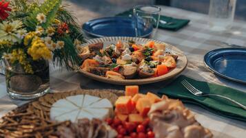Une table dressée avec une variété d’aliments, notamment une assiette de légumes variés, un saladier de fruits et un verre d’eau.