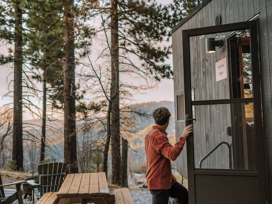 A man opening a door to a cabin with a sign reading "SILVER".