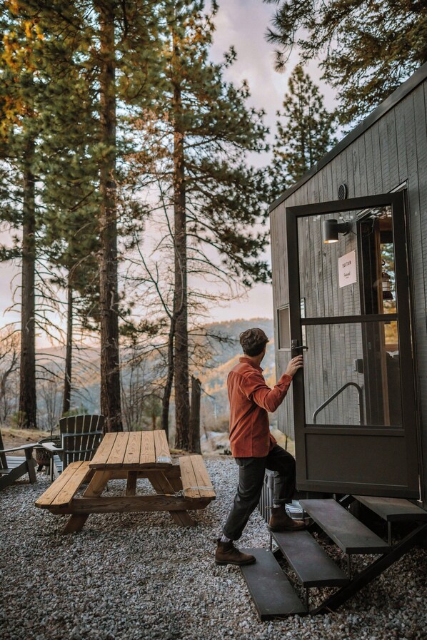 A man opening a door to a cabin with a sign reading "SILVER". - Postcard Cabins Big Bear, Outdoor Collection by Marriott Bonvoy (Running Springs)