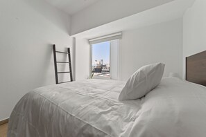 A bedroom with a bed, a window, and a ladder.