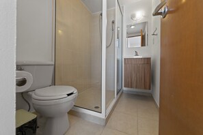 A modern bathroom with a toilet, shower, and sink.
