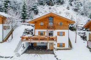 A wooden chalet with a balcony, surrounded by snow-covered trees. - Comfortable Alpine Chalet for 12 (Wald im Pinzgau)