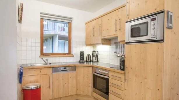 A compact kitchen with wooden cabinets, a microwave, a coffee maker, and a dishwasher. - Schoneben Mountain Holiday Home (Wald im Pinzgau)