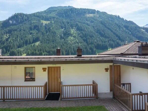 A building with a flat roof, wooden railings, and a door with a window. - Schoneben Mountain Holiday Home (Wald im Pinzgau)