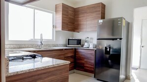 A modern kitchen with wooden cabinets, a stainless steel refrigerator, a microwave, and a granite countertop. - Family Home Near the Beach in Velamar (Altamira)