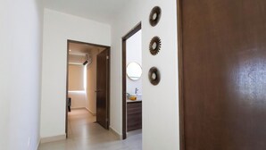 A hallway with a door leading to a bathroom, a mirror, and a wall-mounted decorative item. - Family Home Near the Beach in Velamar (Altamira)