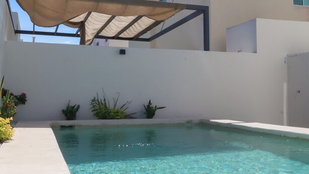 A modern pool area with a clear pool, a pergola, and a white building with a flat roof. - Family Home Near the Beach in Velamar (Altamira)