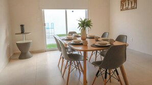 A dining area with a table set for six, surrounded by chairs, a potted plant, and a small side table with a lamp. - Family Home Near the Beach in Velamar (Altamira)